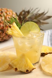 Photo of Glass of tasty pineapple cocktail and sliced fruits on table, closeup