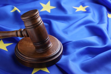 Photo of Wooden judge's gavel on flag of European Union, closeup. Space for text