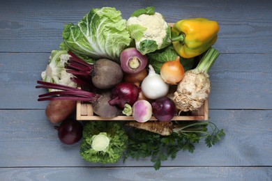 Photo of Different fresh vegetables in crate on wooden table, top view. Farmer harvesting