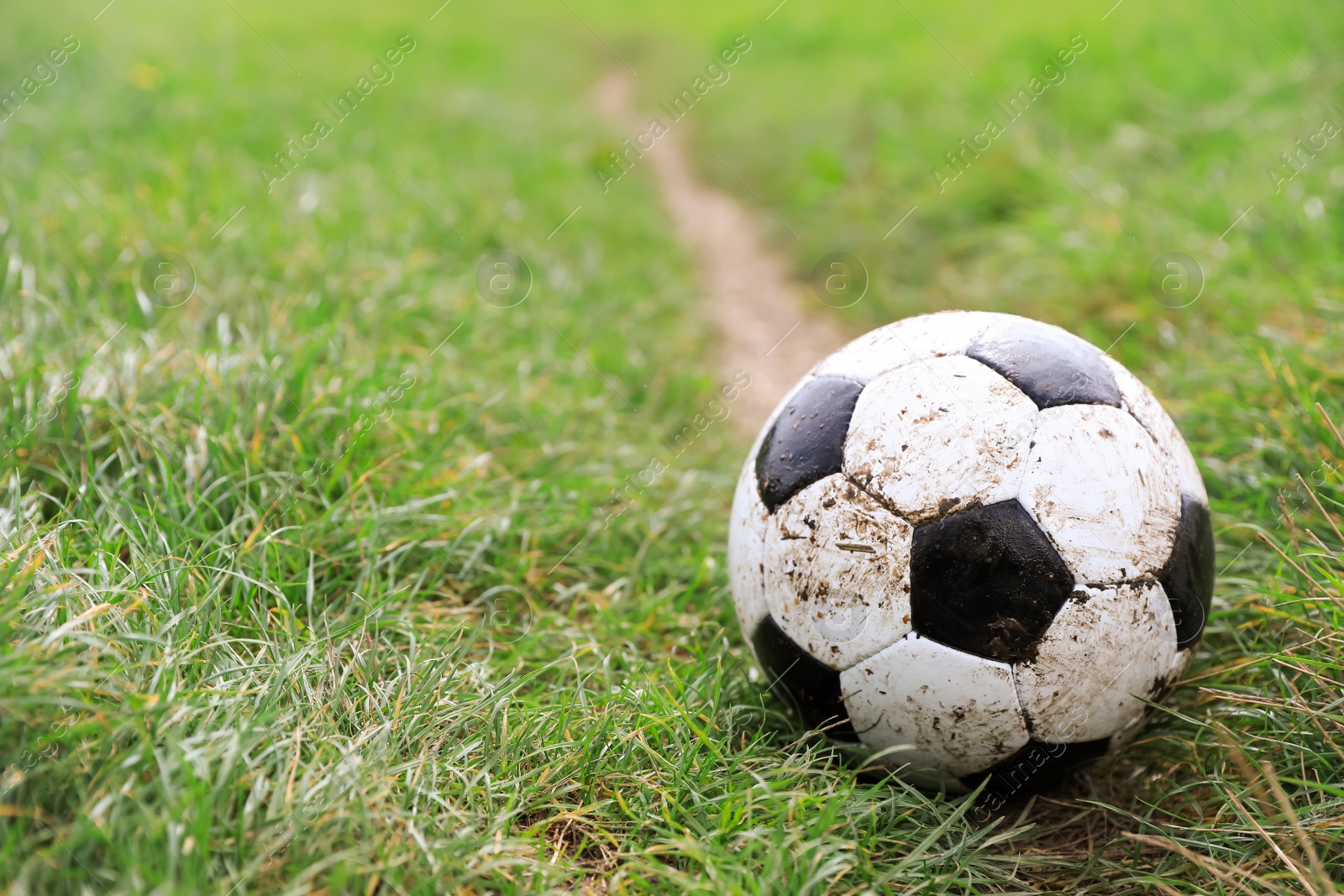 Photo of Dirty soccer ball on green grass outdoors, space for text