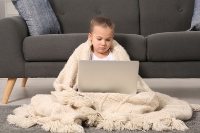 Photo of Little girl using laptop on floor at home. Internet addiction