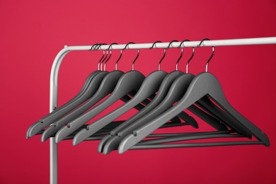 Empty clothes hangers on metal rack against color background