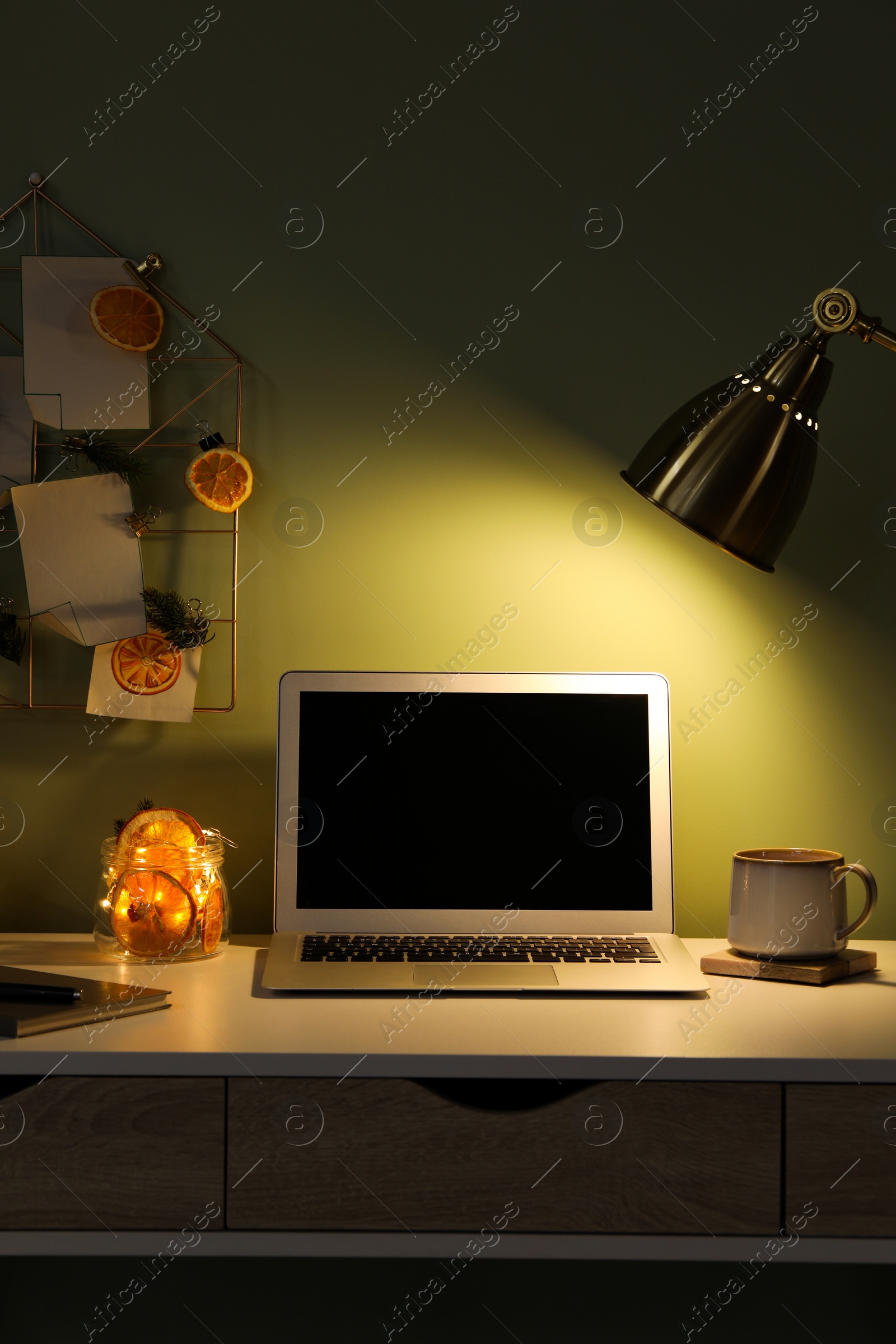 Photo of Stylish workplace with handmade decor made of dry orange slices and notes