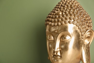 Photo of Beautiful golden Buddha sculpture on green background, closeup. Space for text