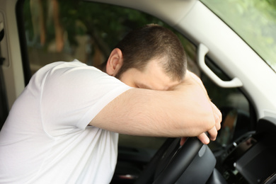 Photo of Tired man sleeping on steering wheel in his car
