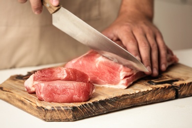 Man cutting fresh raw meat on table, closeup
