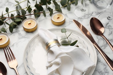 Photo of Beautiful place setting with candles and eucalyptus on white marble table