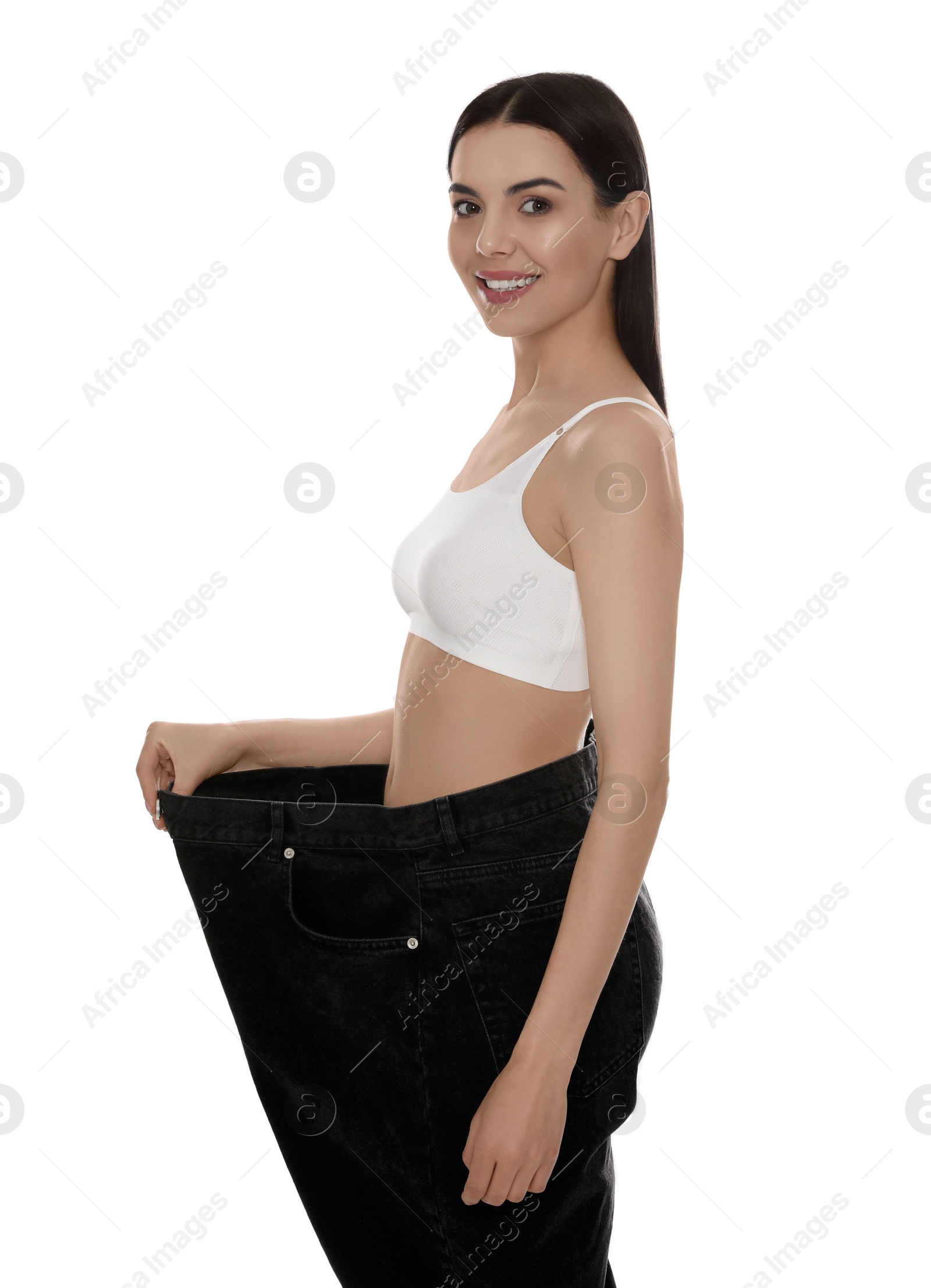 Photo of Young woman wearing big jeans after weight loss on white background