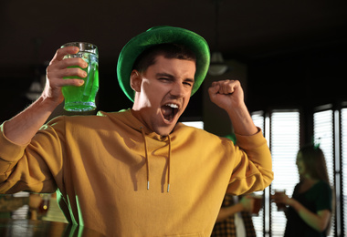 Photo of Emotional man with glass of green beer in pub. St. Patrick's Day celebration