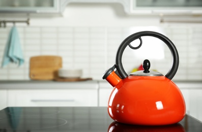 Photo of Modern kettle with whistle on stove in kitchen, space for text