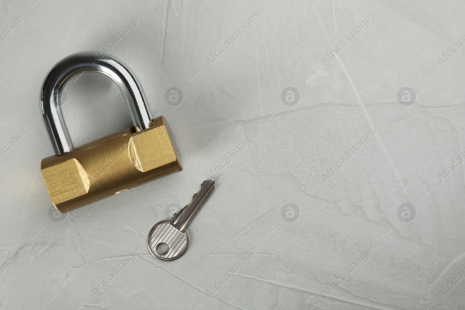 Photo of Modern padlock with key on light grey table, flat lay. Space for text