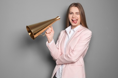 Photo of Young woman with megaphone on grey background