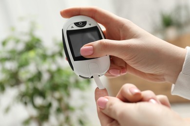 Diabetes. Woman checking blood sugar level with glucometer at home, closeup. Space for text