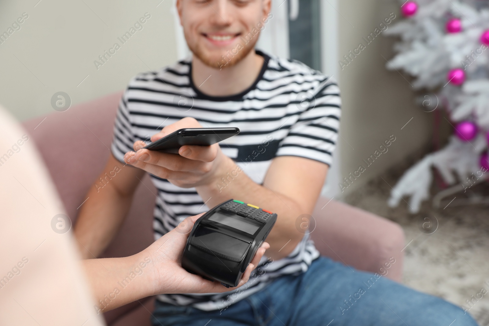 Photo of Client using smartphone and credit card machine for non cash payment in cafe