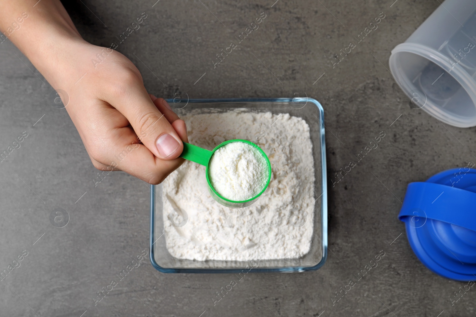 Photo of Man preparing protein shake with powder at grey table, top view