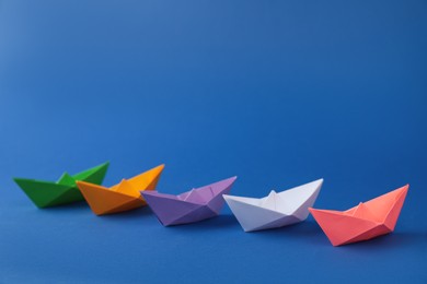 Photo of Many colorful handmade paper boats on blue background. Origami art
