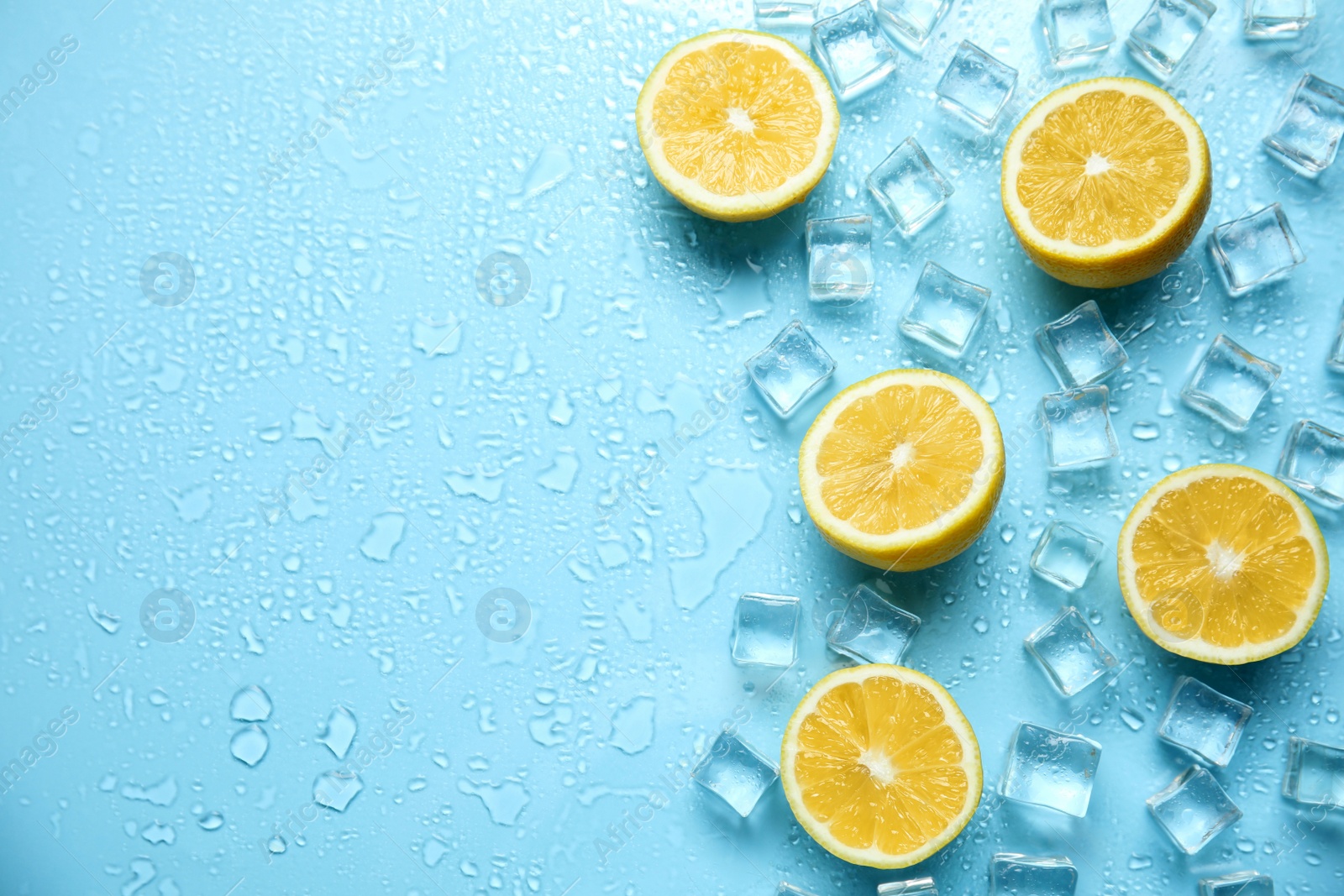 Photo of Ice cubes, cut lemons and space for text on turquoise background, flat lay. Refreshing drink ingredients