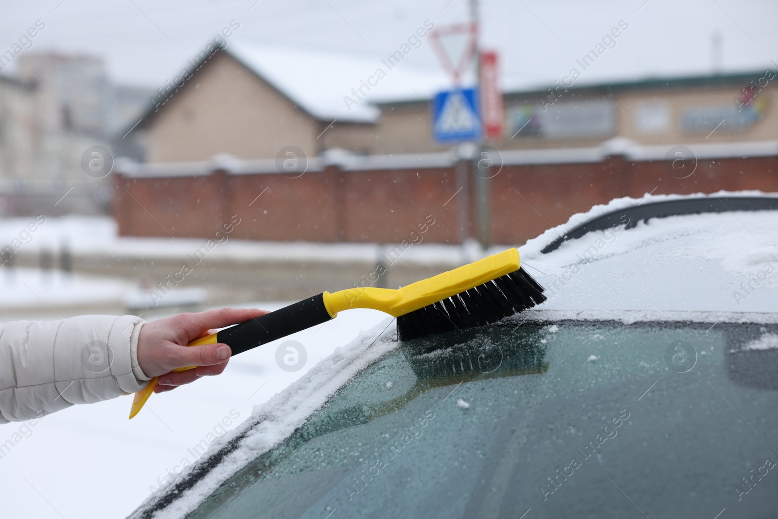 Photo of Man cleaning snow from car windshield outdoors, closeup