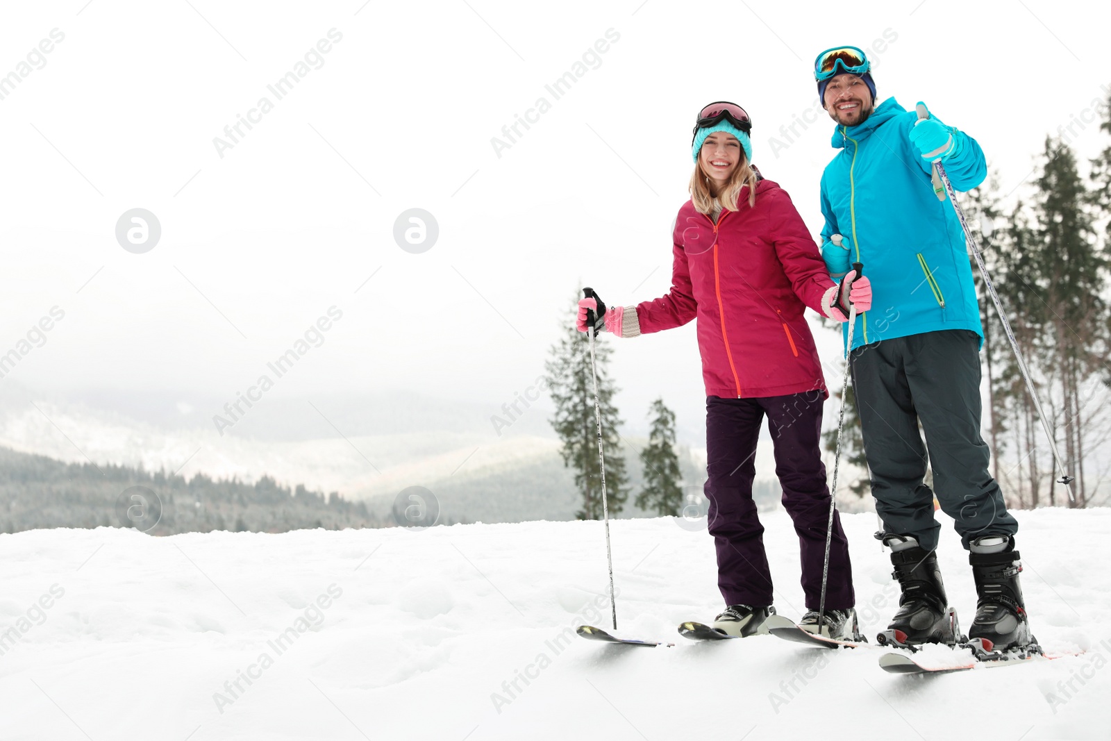 Photo of Couple of skiers on slope at resort, space for text. Winter vacation