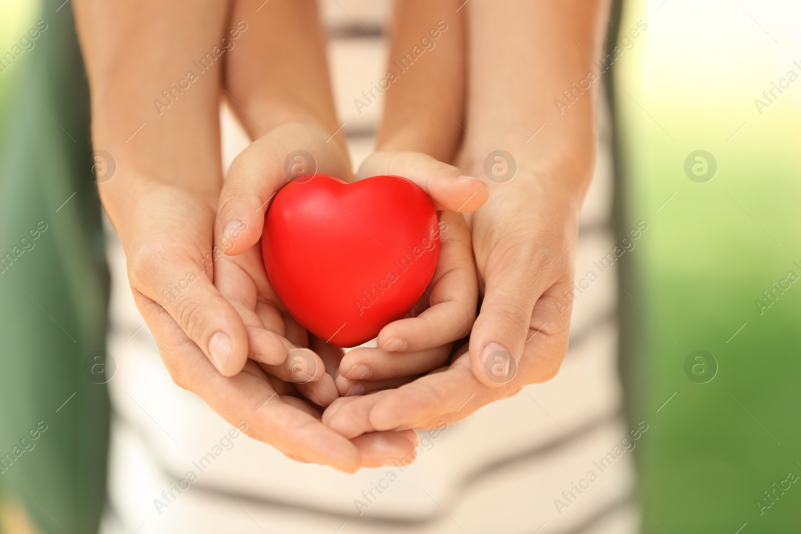 Photo of Adult and child hands holding heart on blurred background, closeup. Family concept