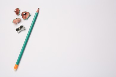 Photo of Graphite pencil, sharpener and shavings on white background, flat lay. Space for text
