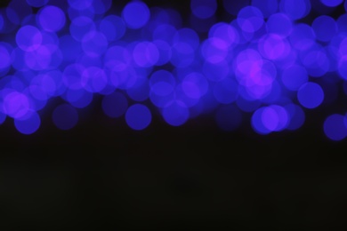 Blurred view of blue Christmas lights on dark background