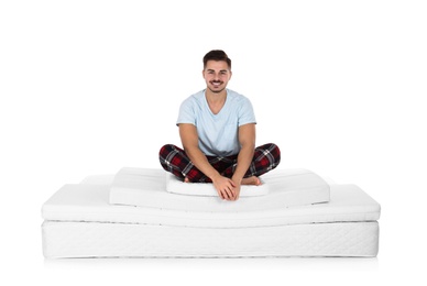 Photo of Young man sitting on mattress pile against white background