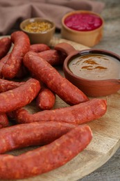 Photo of Delicious sausages, ketchup, mustard and horseradish on wooden table, closeup