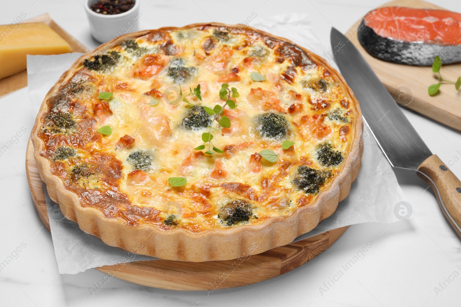 Photo of Delicious homemade quiche with salmon and broccoli on white table