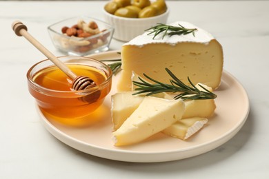 Photo of Tasty Camembert cheese with rosemary and honey on white table