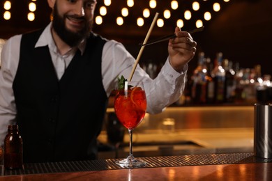 Photo of Bartender making fresh alcoholic cocktail at bar counter, closeup. Space for text