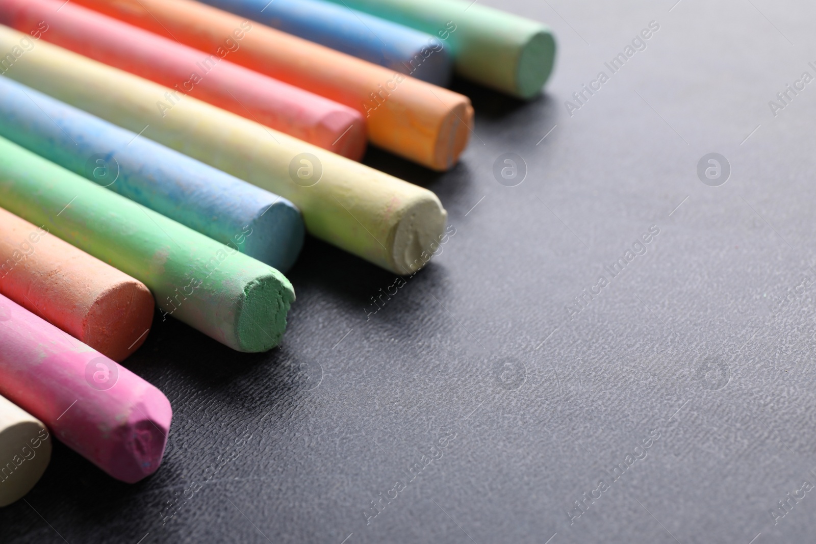 Photo of Pieces of color chalk on blackboard, space for text