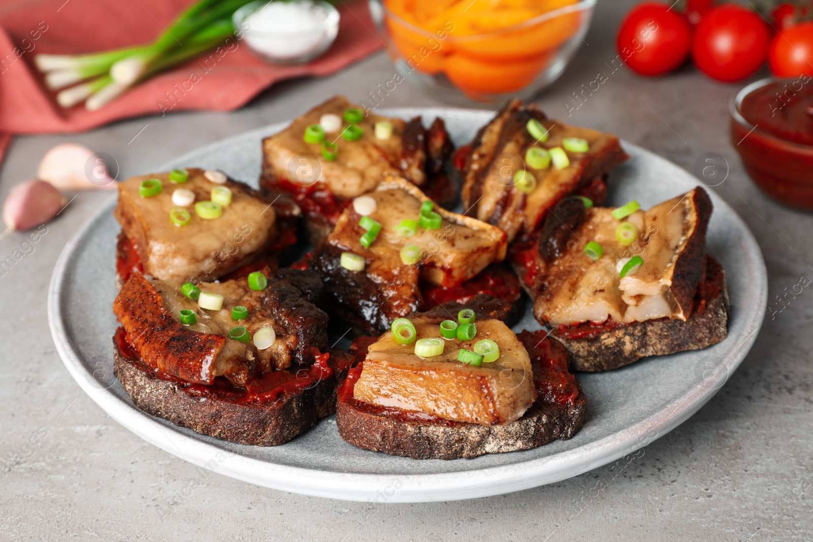 Photo of Tasty sandwiches with fried pork fatback slices on grey table