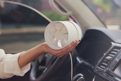 Woman with portable fan in car on hot summer day, closeup