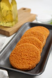 Uncooked breaded cutlets on white wooden table. Freshly frozen semi-finished product