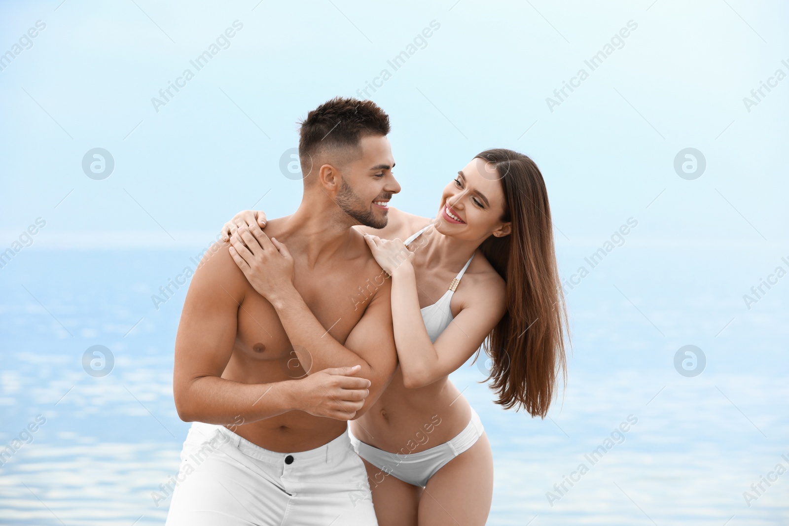 Photo of Young woman in bikini with her boyfriend on beach. Lovely couple