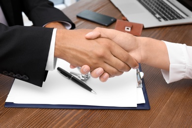 Photo of Woman shaking hands with real estate agent on meeting over table