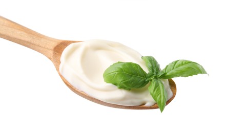 Photo of Wooden spoon with tasty mayonnaise and basil isolated on white