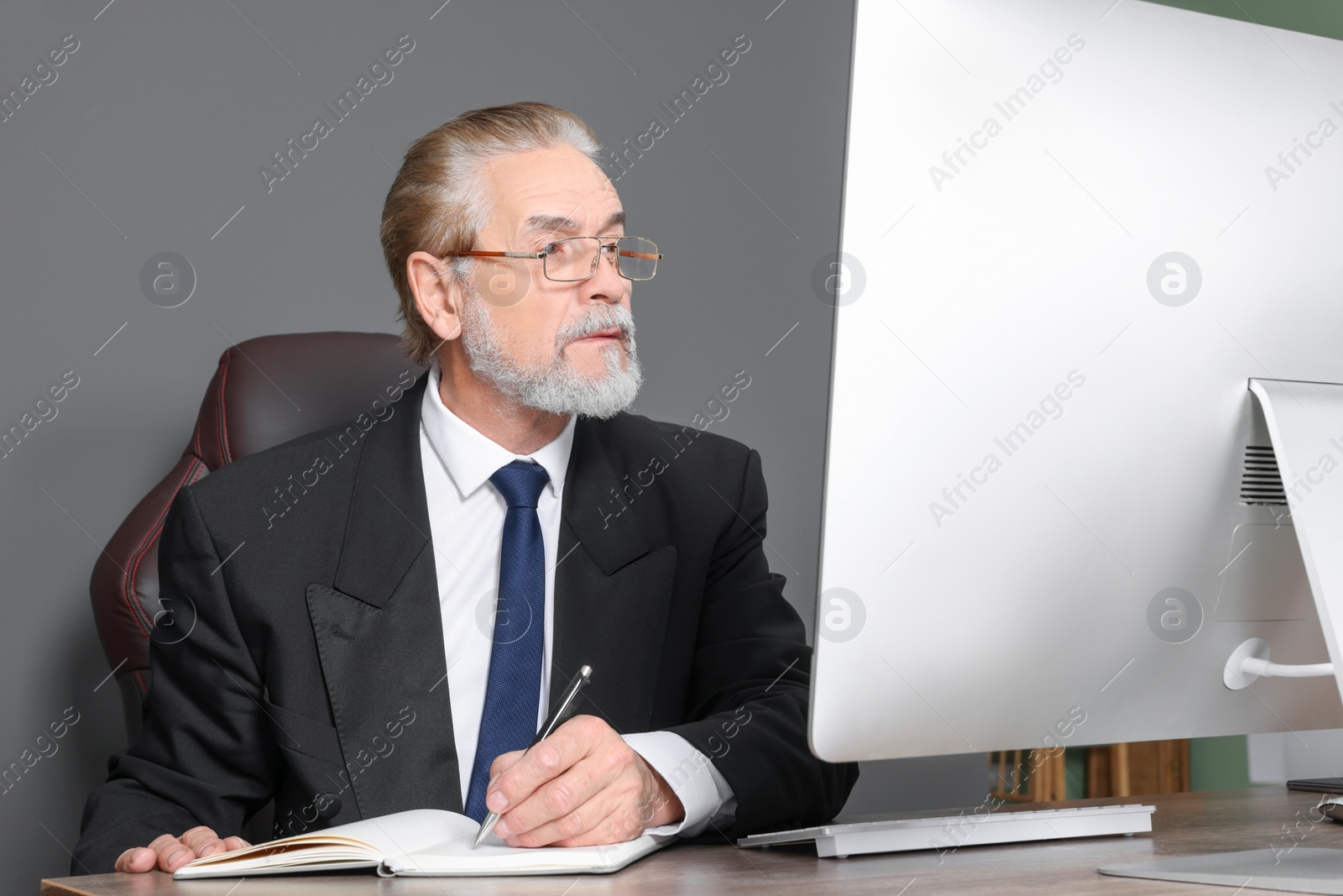 Photo of Senior boss working at wooden table in modern office