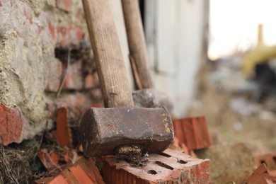 Sledgehammer near brick wall outdoors, closeup. Space for text