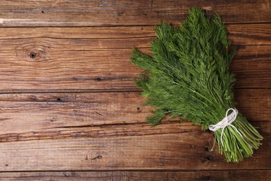 Bunch of fresh green dill on wooden table, top view. Space for text