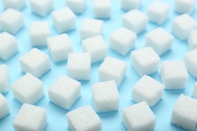 White sugar cubes on light blue background, closeup