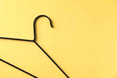 Photo of One black hanger on yellow background, top view. Space for text