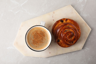 Photo of Delicious coffee and bun on marble table, top view. Sweet pastries