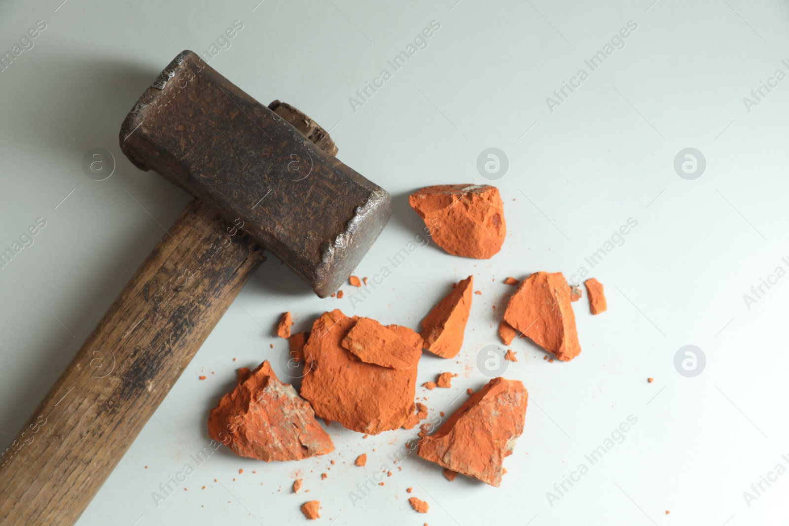 Photo of Sledgehammer and pieces of broken brick on grey background, top view. Space for text