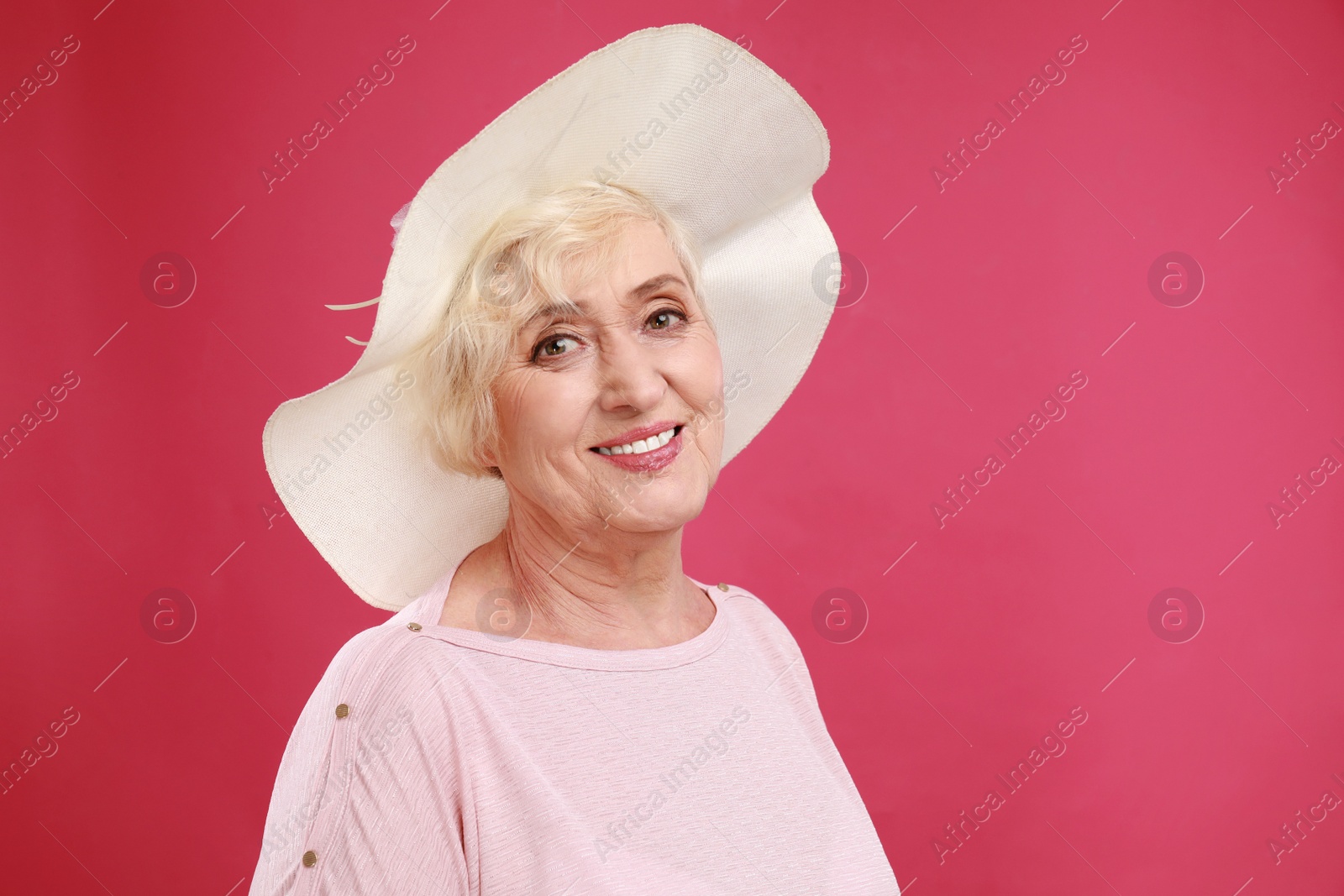 Photo of Senior woman with hat on crimson background