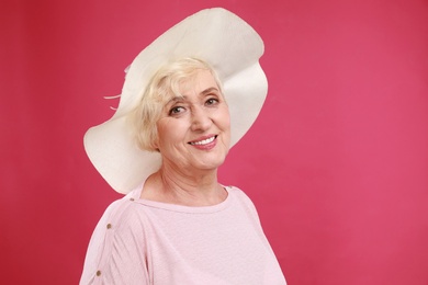 Senior woman with hat on crimson background