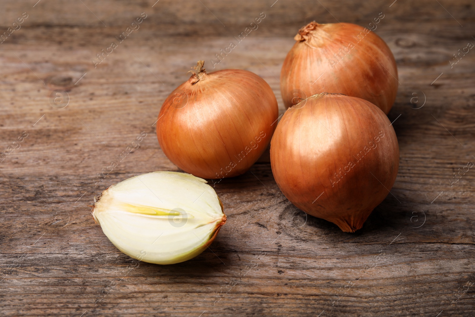 Photo of Ripe onions on rustic wooden table, closeup