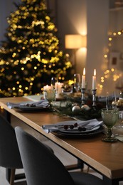 Christmas table setting with festive decor and dishware in room