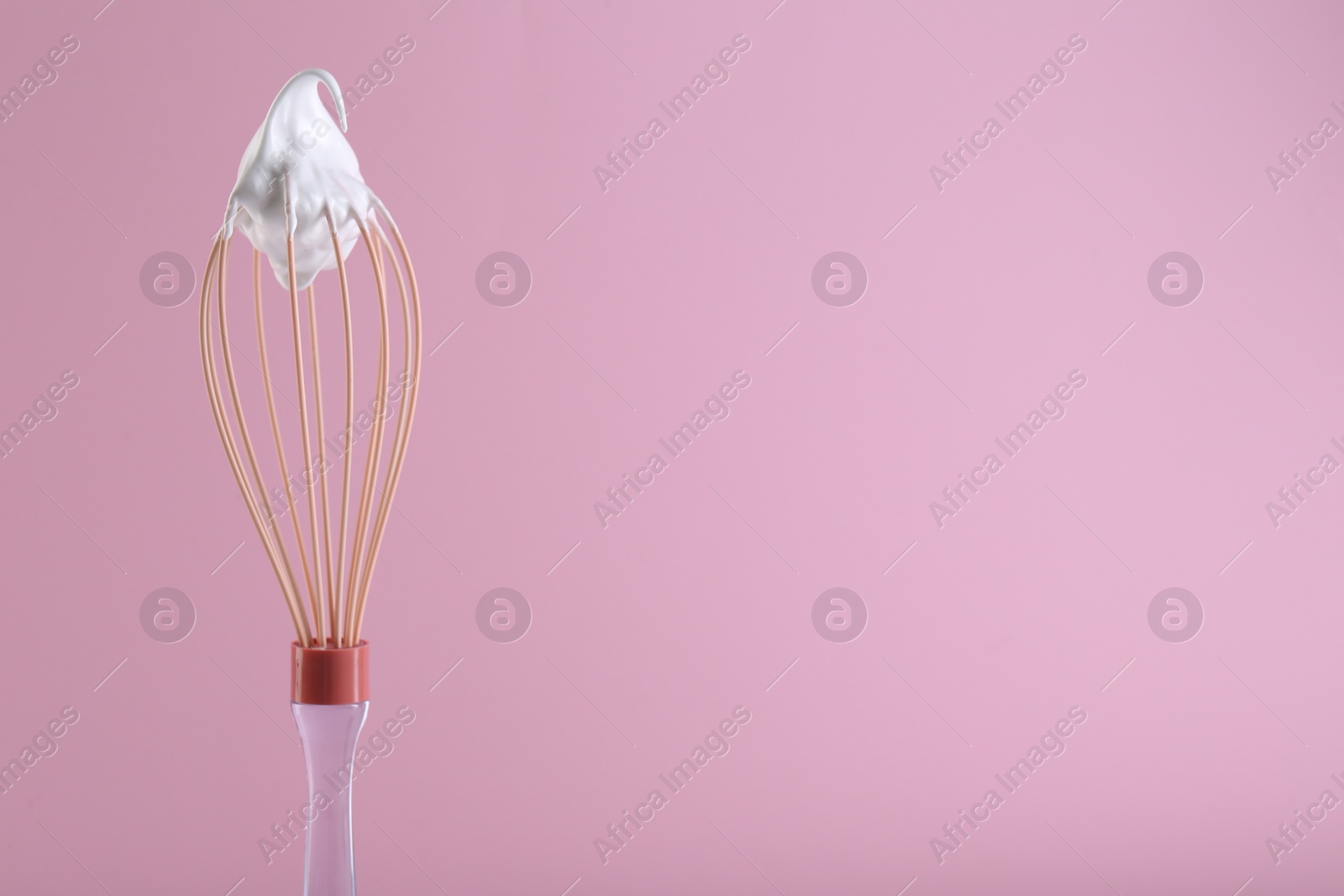 Photo of Whisk with whipped cream on pink background. Space for text
